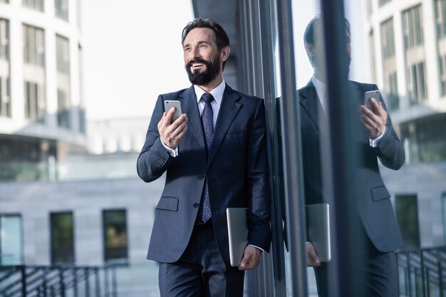 Urban lifestyle. Positive handsome businessman using his laptop outdoors while smiling