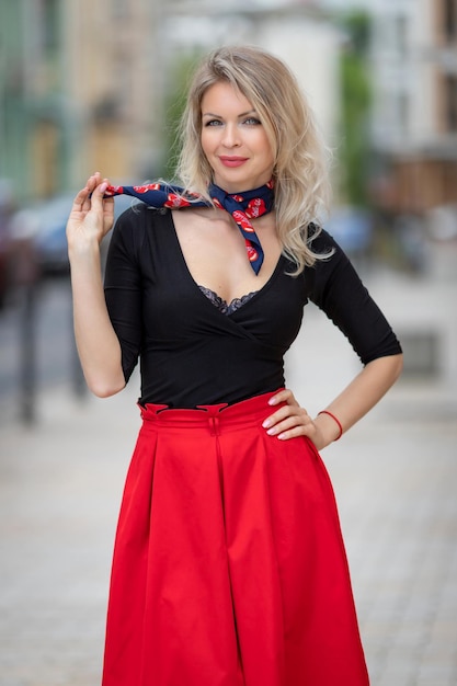 Городской портрет красивой сексуальной молодой блондинки в красной юбке и с глубоким декольте высокого качества