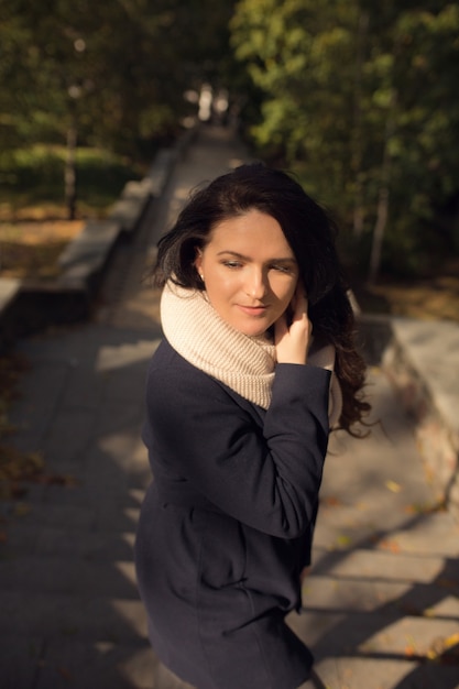 Urban portrait of elegant brunette model with long wavy hair walking on the street with stairs