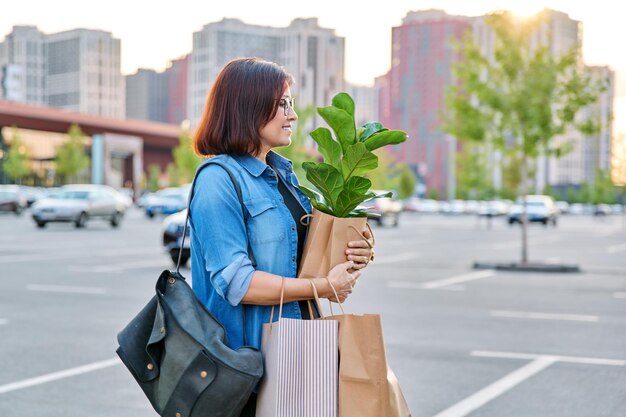 Urban portrait of middle aged woman with shopping bags in mall parking