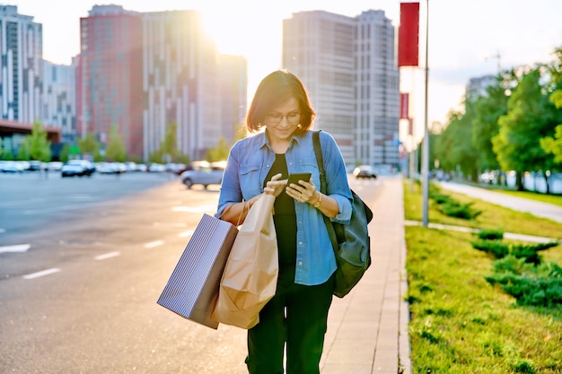 Urban portrait of middle aged woman with shopping bags in mall parking