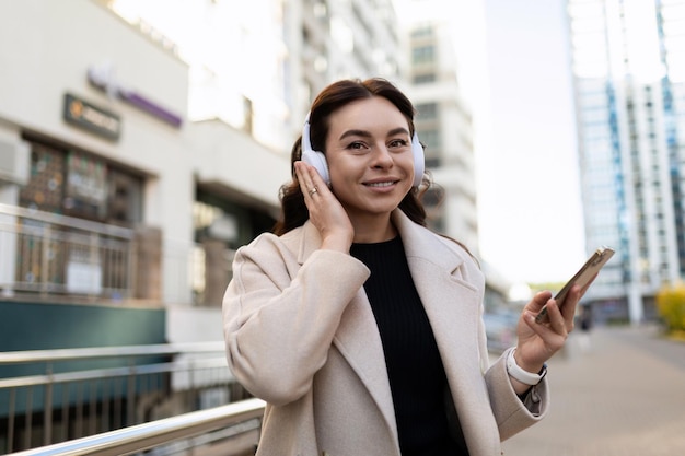 Urban stylish girl walks around the city and listens to music