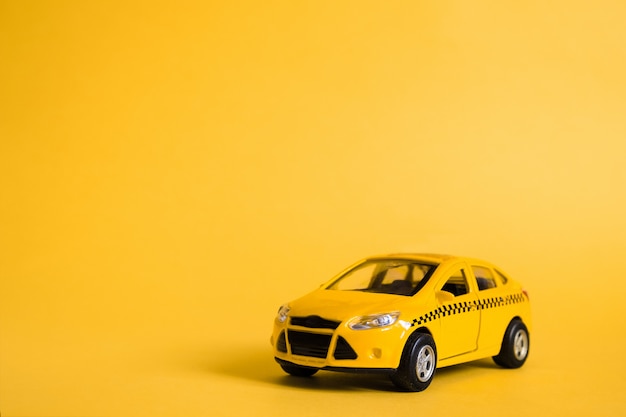 Urban taxi and delivery service concept. Toy yellow taxi car model.