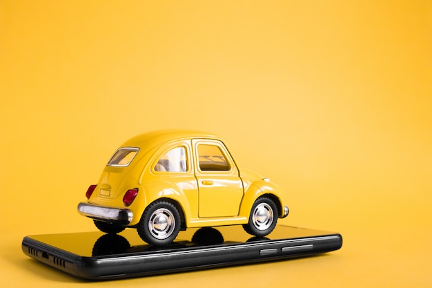 도시 택시 모바일 온라인 응용 프로그램 개념. 장난감 노란색 택시 자동차 모델. 손 택시 서비스 애플 리 케이 션 스마트 폰 디스플레이에 들고.