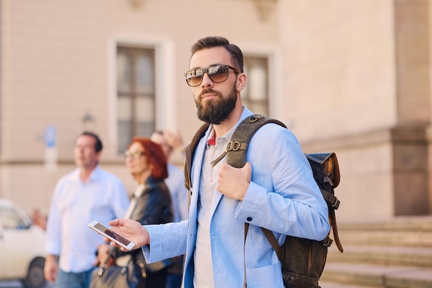 Urban traveller bearded man with a backpack using smart phone.