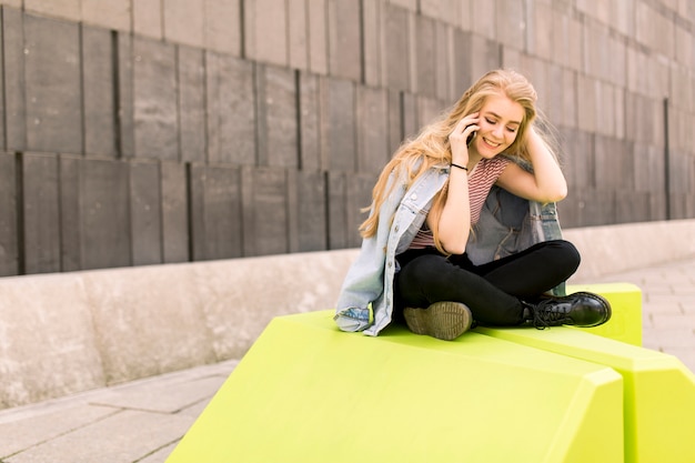 Urban young female student sitting outside and use the phone