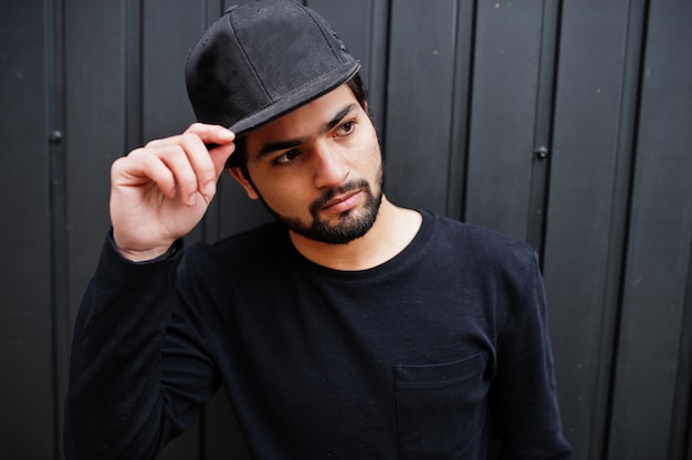 Photo urban young hipster indian man wear all in black. cool south asian guy in full cap.