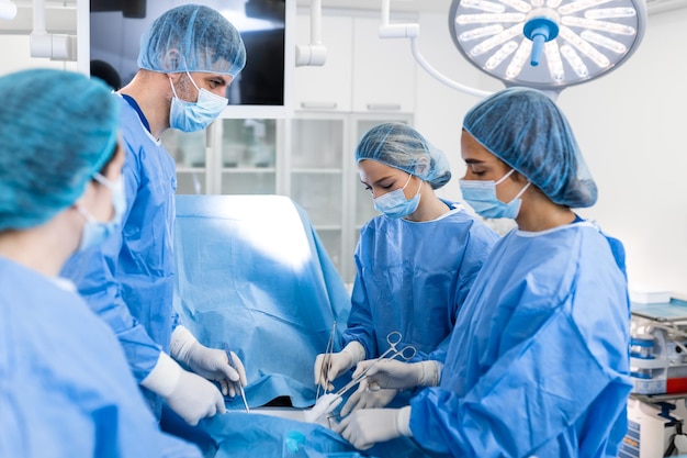 Urgent surgery Professional smart intelligent surgeons standing near the patient and performing an operation while saving his life