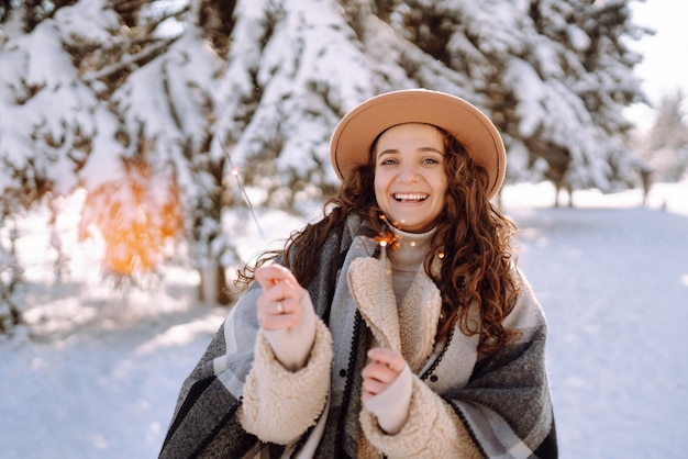 Urly lady with sparklers in the hands Fashion young woman in the snow forest