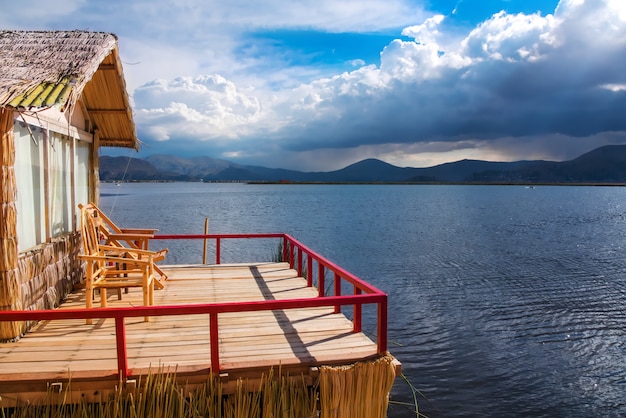 Uros floating island and Totora traditional boat on Titicaca lake near Puno city, Peru