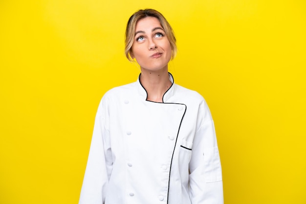 Uruguayan chef woman isolated on yellow background and looking up