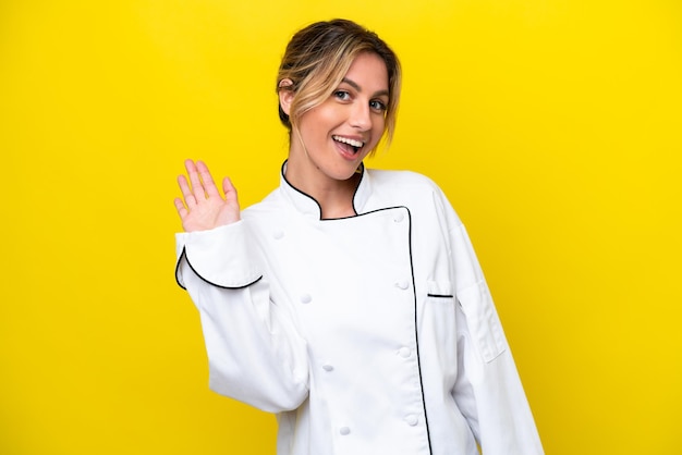 Uruguayan chef woman isolated on yellow background saluting with hand with happy expression