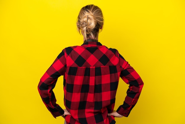 Uruguayan photographer woman isolated on yellow background in back position