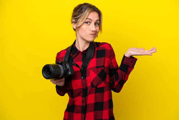 Photo uruguayan photographer woman isolated on yellow background having doubts while raising hands