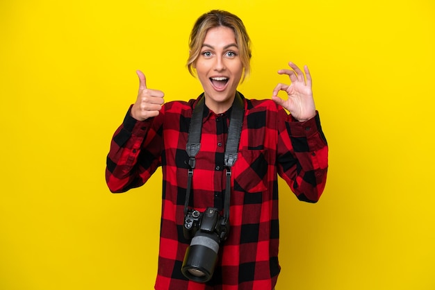 Uruguayan photographer woman isolated on yellow background showing ok sign and thumb up gesture