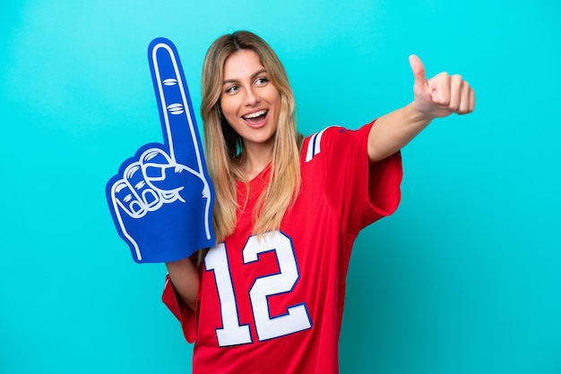 Uruguayan sports fan woman isolated on blue background giving a thumbs up gesture