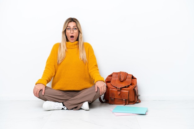 Uruguayan student woman sitting one the floor isolated on white background with surprise facial expression