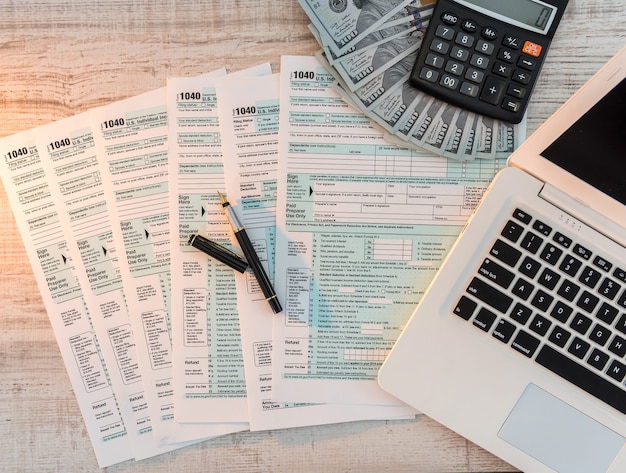 Photo us 1040 tax form with pen, dollar and laptop at office. tax time. accounting concept