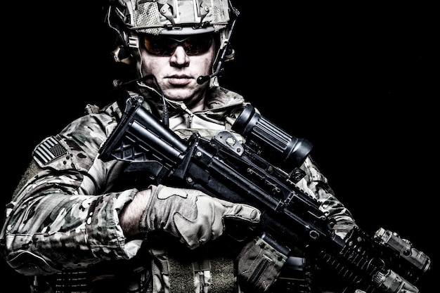 US army soldier, marine rider, special forces fighter in combat uniform, helmet and glasses, radio headset, armed assault rifle with night vision, thermal imagining, optical sight on black background