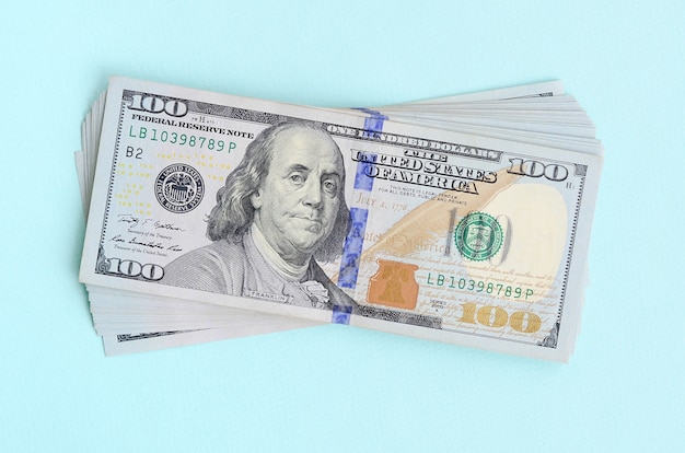 US dollar bills of a new design with a blue stripe in the middle is lies on a light blue background