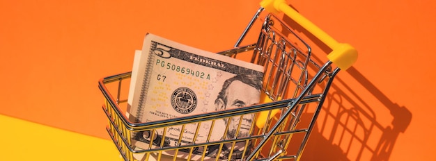 Photo us dollar paper currency 5 banknote money shopping trolley cart on colorful orange yellow background