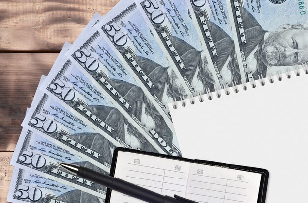 US dollars bills fan and notepad with contact book and black pen