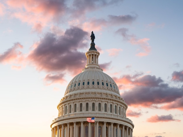 新しい日の夜明けに太陽が昇ると、米国旗がワシントンDCの米国議会議事堂の前を飛びます。