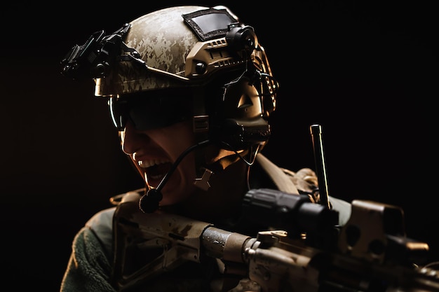 黒い暗い背景に対して射撃する準備ができている目標を見ている米国の特殊部隊の兵士
