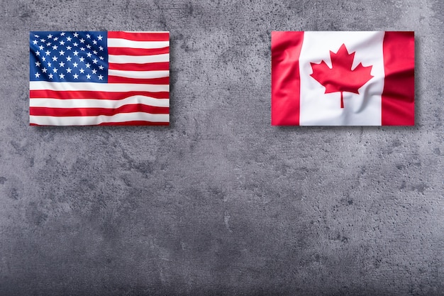 USA flag and Canada flag on concrete background.