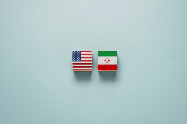 木製の立方体ブロックの米国旗とイランの旗。アメリカ合衆国とイランは核兵器とホルムズ海峡で紛争を抱えています。