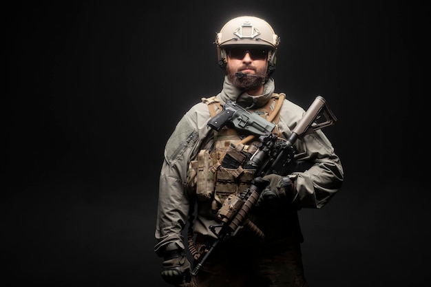 USA soldier in a military suit with a rifle against a dark background