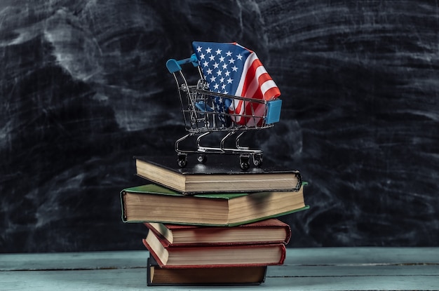 Usa vlag in winkelwagentje op stapel boeken. Schoolbord achtergrond