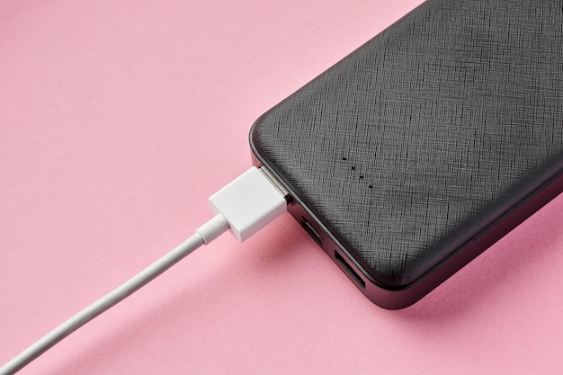 Foto usb-connector is aangesloten op powerbank op een roze achtergrond opladen van gadgets