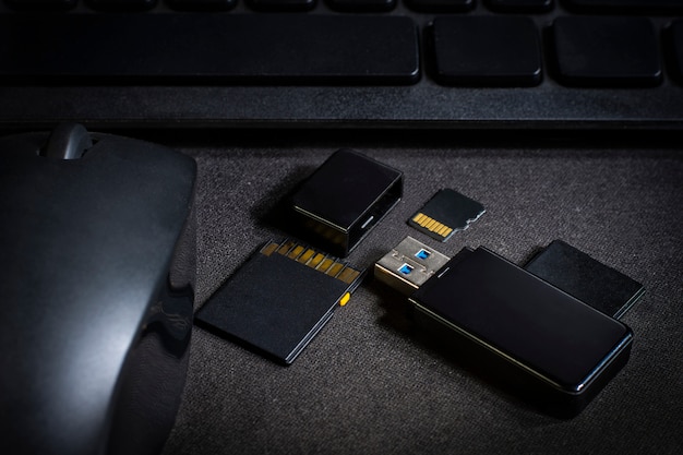 USB flash drive and memory card above computer. place on Office desk / selective focus