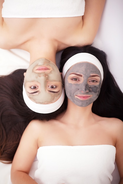 Использование маски для лица двух молодых женщин в салоне красоты