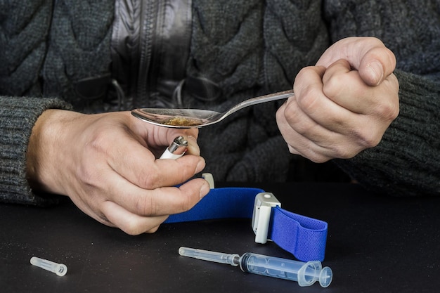 The use of illegal drugs drugs A man preparing heroin using a spoon and a lighter Illegal drugs