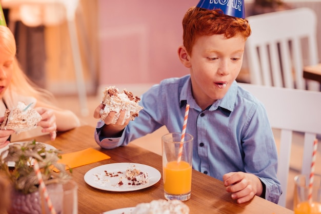 Use serviette. Handsome red-haired boy looking aside while talking to his friend