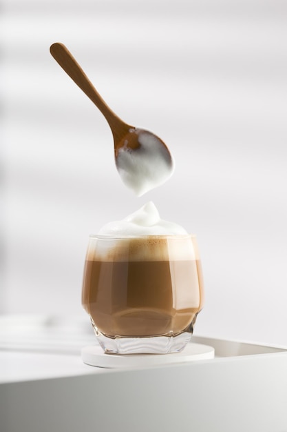 Use a wooden spoon to pour milk froth into a cappuccino cup