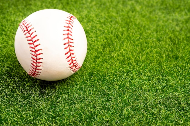 A used baseball on the clear green grass turf closeup as macro shot with copy space