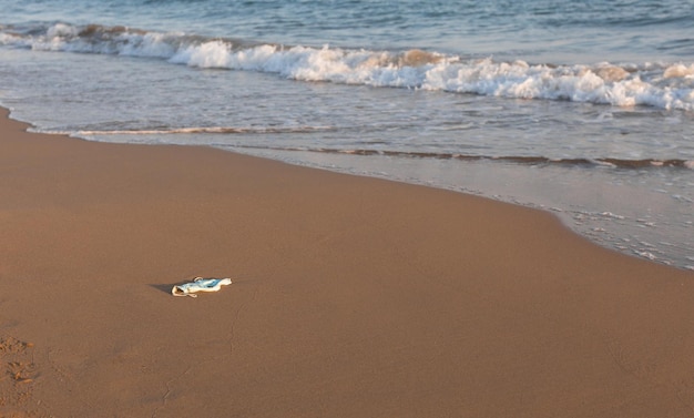写真 海岸線のゴミに使用された使い捨てマスクは海の健康を脅かします