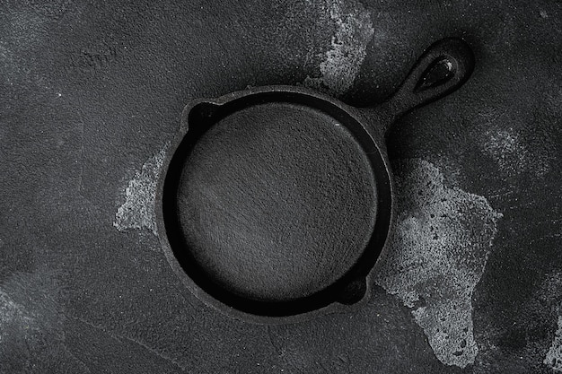 Used old empty frying pan set with copy space for text or food with copy space for text or food, top view flat lay, on black dark stone table background