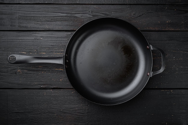 Photo used old empty frying pan set with copy space for text or food with copy space for text or food, top view flat lay, on black wooden table background