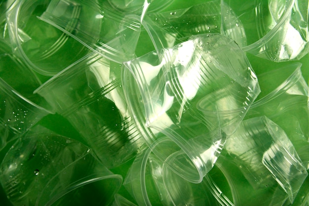 Используется пластиковый стаканчик на зеленом фоне, концепция переработки, минимальный дизайн