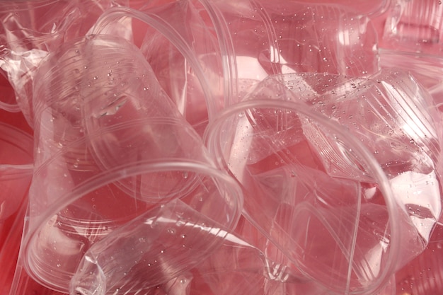 Tazze di plastica usate su sfondo rosa.