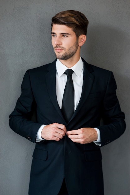 Used to success. Confident young businessman adjusting his jacket and looking away