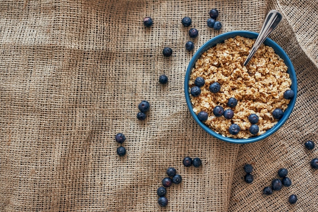 Useful breakfast. Top view of healthy and useful breakfast cereals with blueberries, oats in bowl on isolated. Healthy snack or breakfast in the morning. Metal spoon in muesli