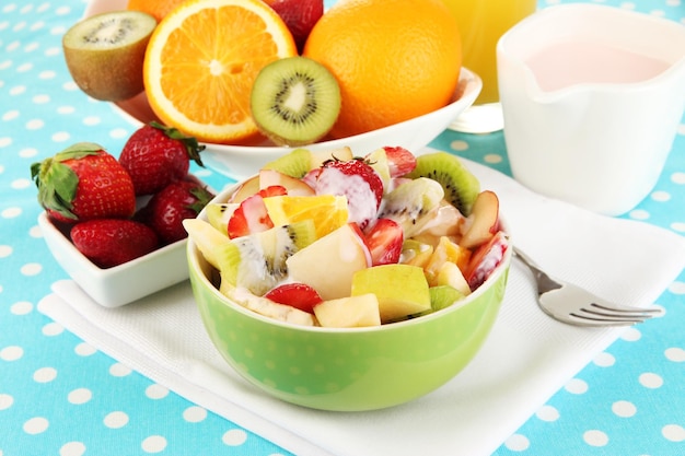 Useful fruit salad of fresh fruits and berries in bowl on tablecloth closeup