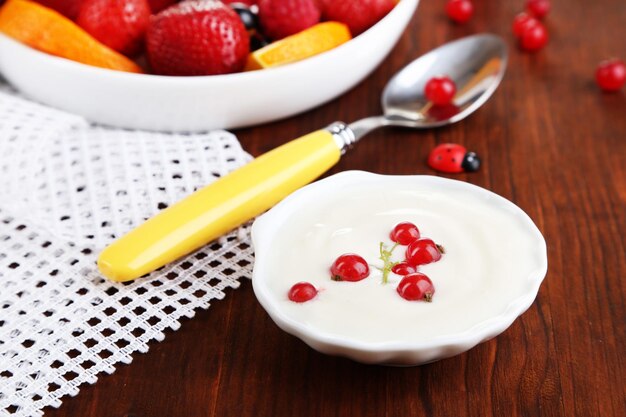 Useful fruit salad in plate on wooden table closeup