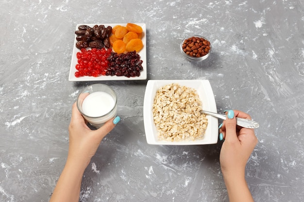 Useful and healthy breakfast The girl took milk to pour it into oatmeal