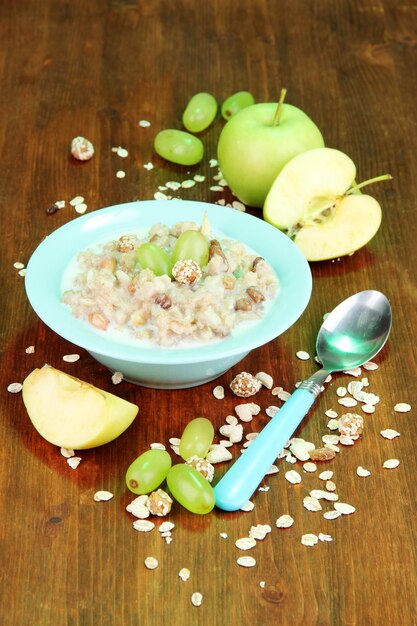 Useful oatmeal in bowl with fruit on wooden table closeup